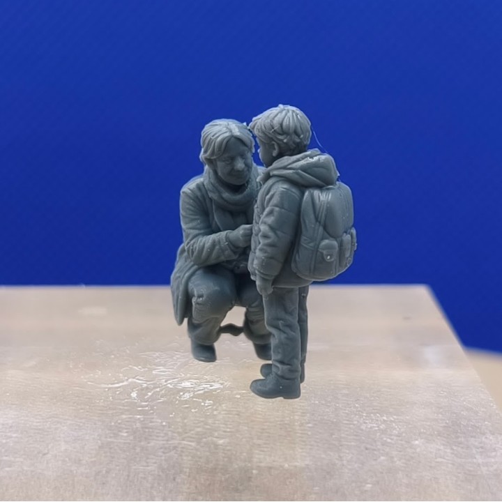 Scène 1:43 d'une maman fermant la veste de son garçon avec sac à dos