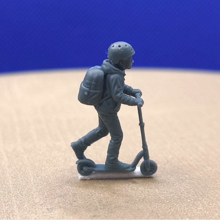 Enfant en trottinette avec casque et sac à dos à l’échelle 1:43, vue de profil