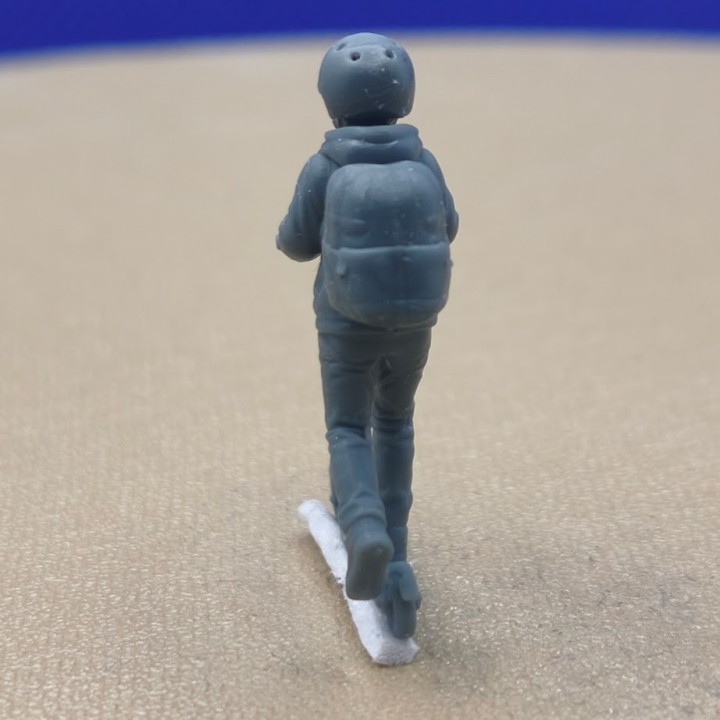 Enfant en trottinette avec casque et sac à dos à l’échelle 1:43, vu de dos