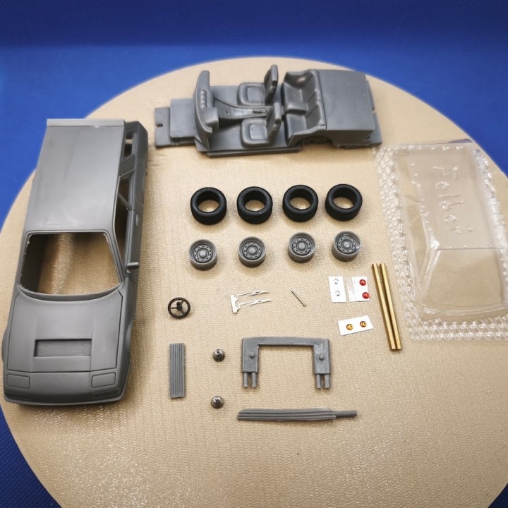 Éléments du kit Ferrari 365 Felber 1:43 disposés à plat avec carrosserie, roues et vitrage
