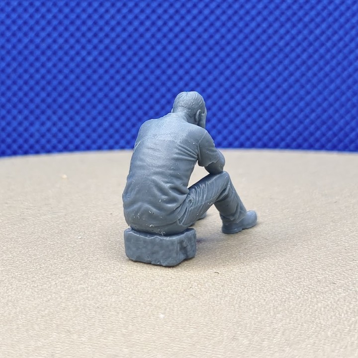 Homme assis les mains sur le visage à l’échelle 1:43 vu de dos