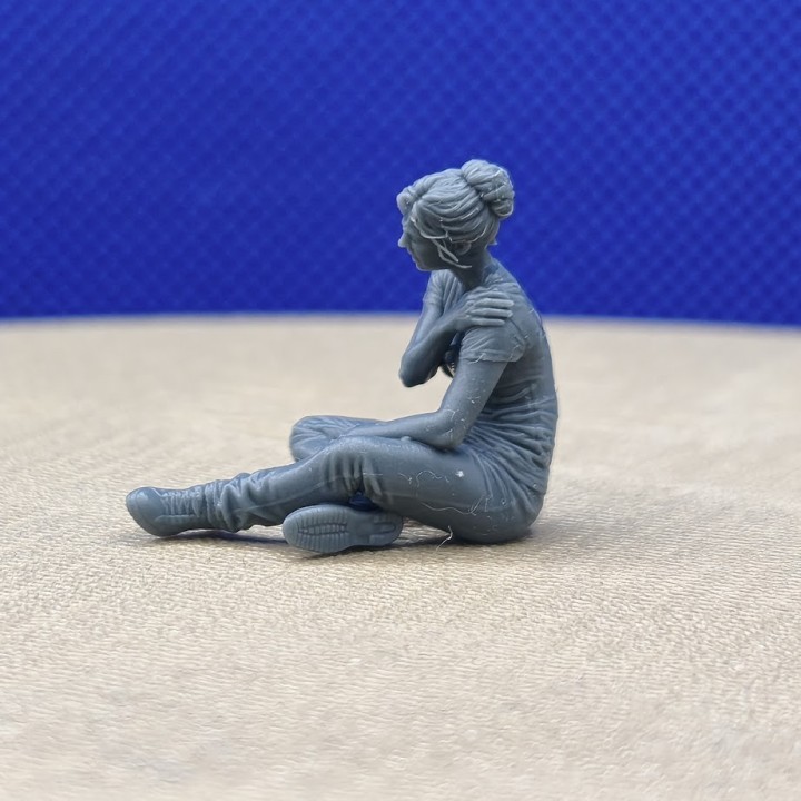 Femme assise se tenant l’épaule, personnage 1:43 présenté de profil