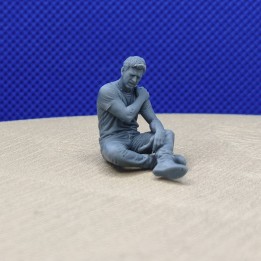Homme assis au sol se tenant l'épaule, vu de face trois quarts