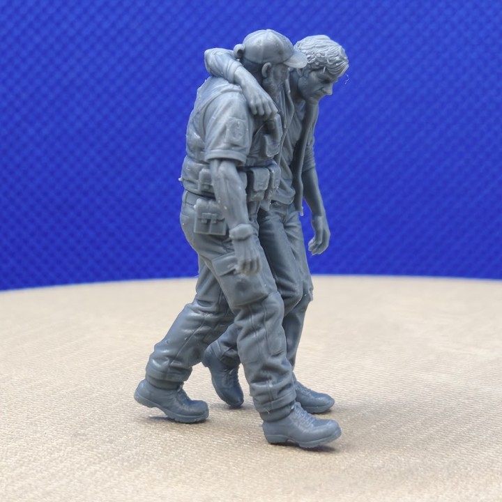 Diorama 1:43 avec agent de sécurité soutenant un homme blessé, vue latérale