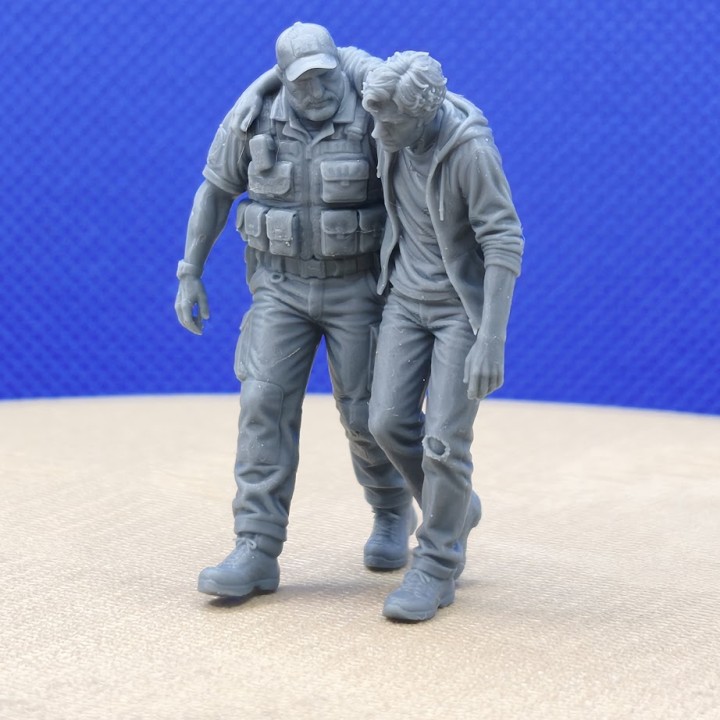 Agent de sécurité aidant un homme blessé au jean troué, diorama 1:43 en vue trois-quarts