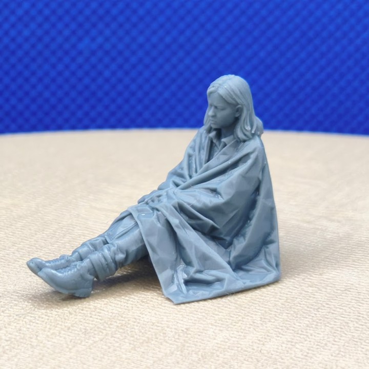 Femme assise enveloppée dans une couverture de survie 1:43, vue latérale