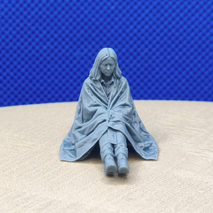 Femme assise avec une couverture de survie à l’échelle 1:43, vue de face