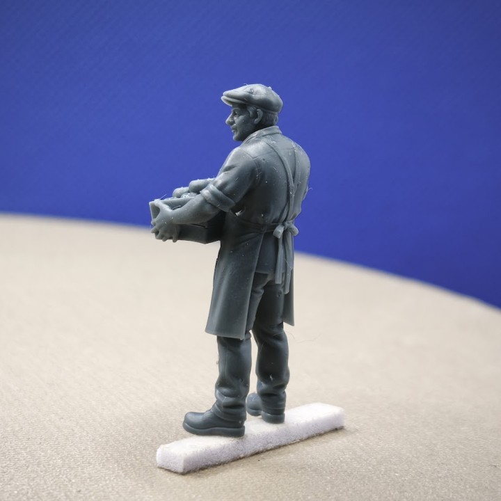 Maraîcher avec cagette de pommes dans un diorama miniature au thème du marché