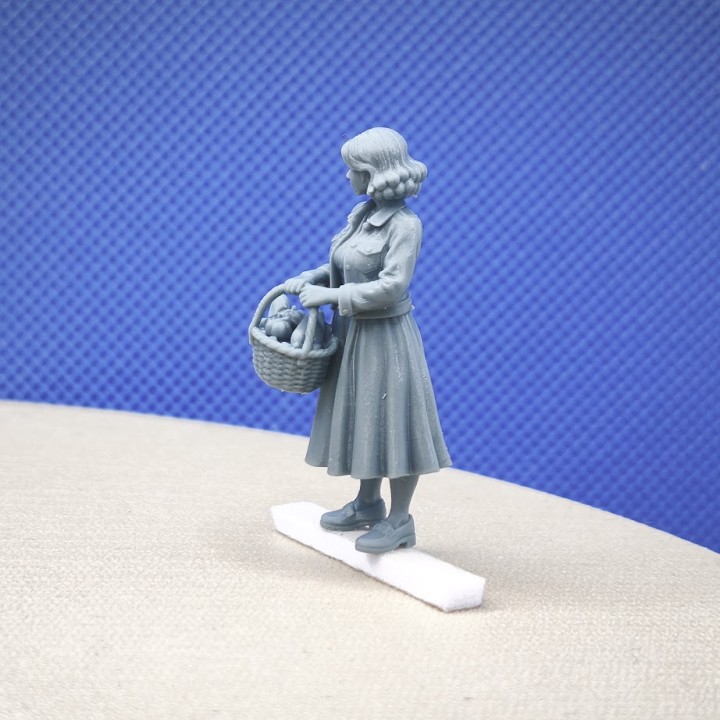 Femme miniature portant un panier de courses dans une scène de marché au 1:43