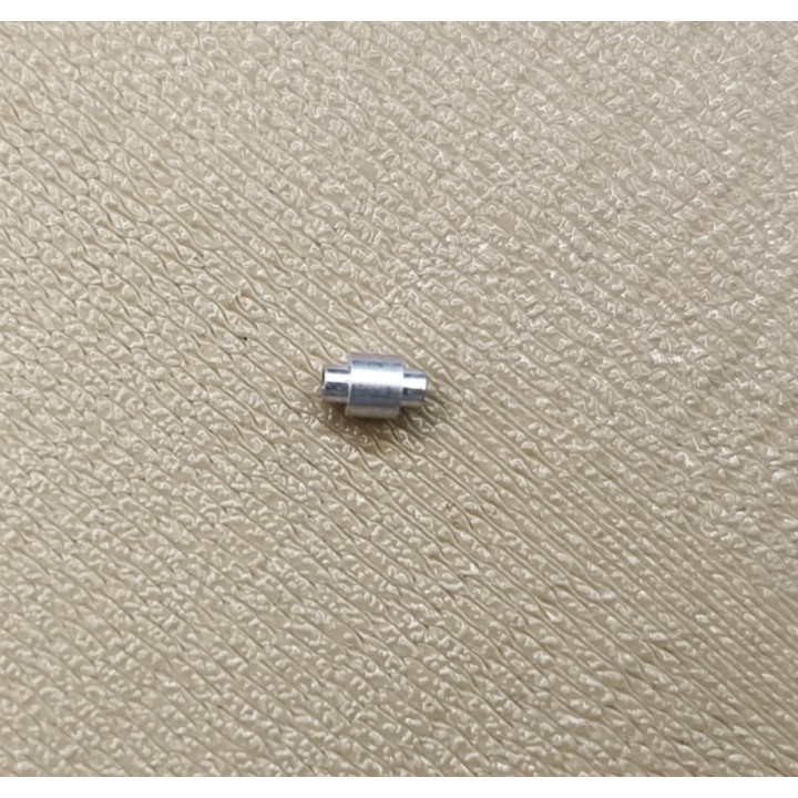 Un raccord cylindrique en aluminium pour miniature présenté sur une surface texturée
